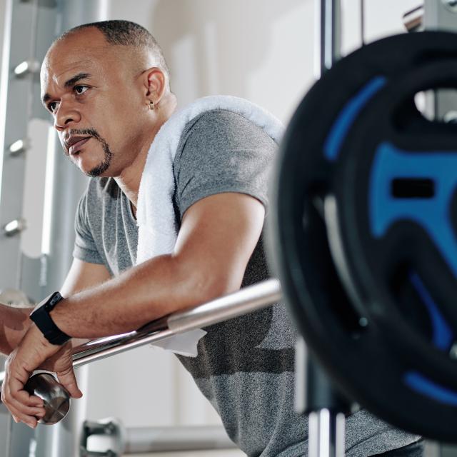 Mature man leaning on barbell